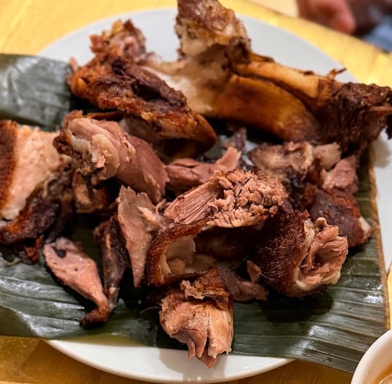 Crispy pata chopped for the table, served on a banana leaf.